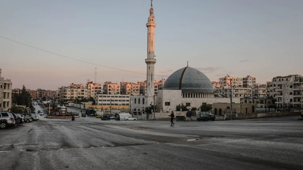 A boy carrying bread through a dimly lit Syrian street at dusk