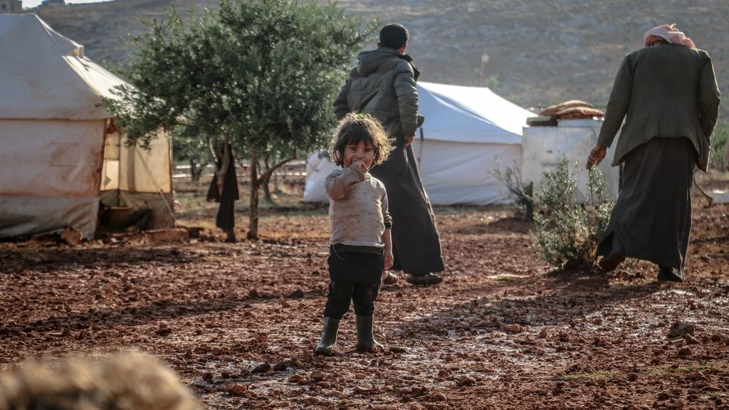 Syrian families waiting at a water distribution point in northern Syria
